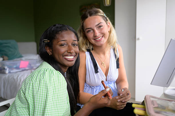 Smiling portrait of two young women applying make-up together at home Multiracial 19-year-old female friends portrait, looking at camera, smiling together teenage girl before and after make up stock pictures, royalty-free photos & images