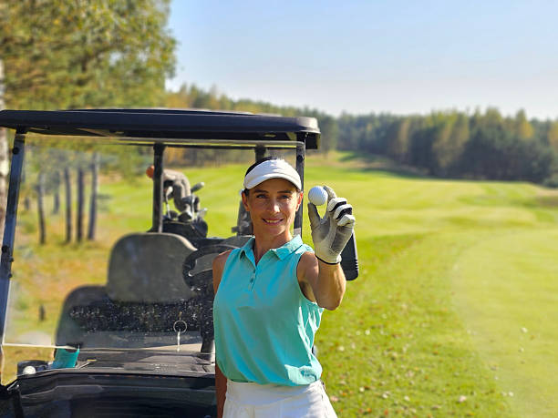 istock Golfer smiling while holding a golf ball near a golf cart 2224659683