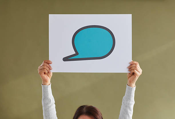 istock Woman holding up a blue blank mockup paper speech balloon or text message bubble 2224659908
