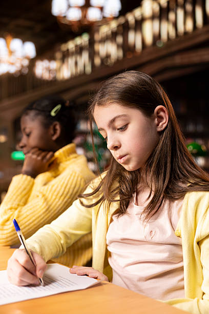 istock Scholars writing essays in library in order to finish their homework assignments 2224662440