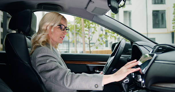 istock Business woman driver sitting in car, using touch screen and tapping on electronic dashboard of luxury car while having mobile conversation. 2224664122