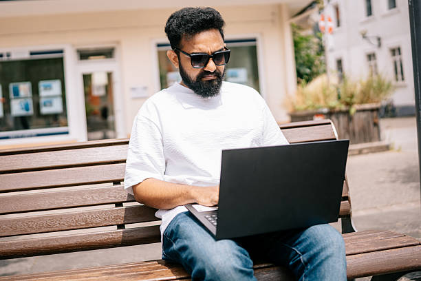 istock Focused man working on a laptop outdoors on a sunny day. 2224664551