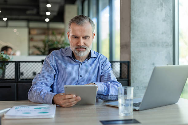 istock Smiling handsome mature businessman manager sitting in office with tablet computer 2224665902