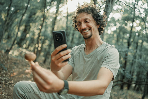 istock Man Smiling While Using Smartphone in Forest Capturing Outdoor Moments 2224666527