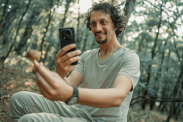 istock Man Seated in Forest Identifying a Mushroom with Smartphone Camera 2224666528