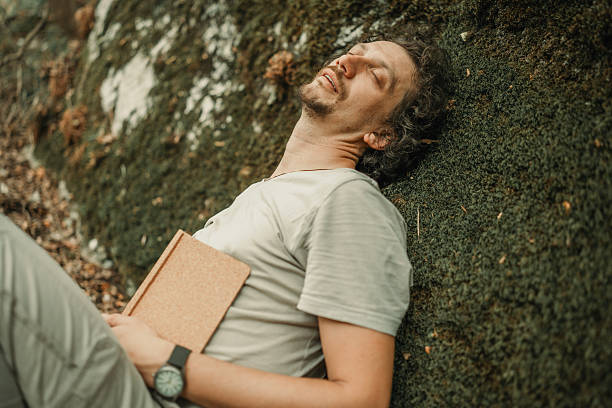 istock Man Relaxing Outdoors with Journal Against Mossy Hillside 2224667645