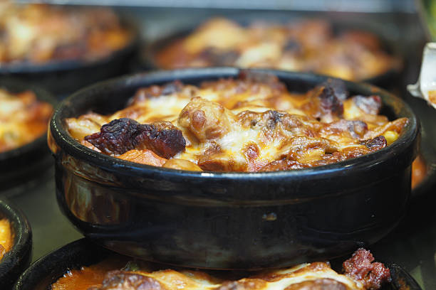 A rich and savory baked dish is steaming in a black bowl, inviting hunger.