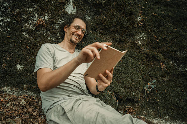 istock Man Relaxing Outdoors Reading a Notebook Amidst Nature's Serenity and Greenery 2224671681