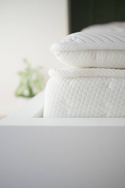 istock Freshly stacked white bedding on a wooden bed frame in a cozy room 2224674112