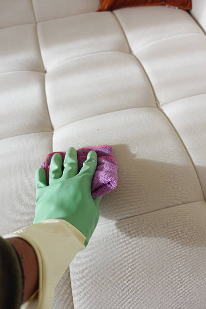 istock Cleaning a light-colored couch with a cloth and gloves 2224676099