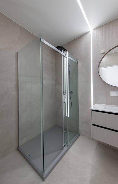 istock Modern Bathroom With Glass Shower, Vanity Unit, and Circular Mirror 2224676516