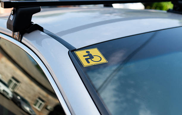 istock Yellow disabled sign sticker on car windshield indicating vehicle accessibility for persons with disabilities. 2224677067