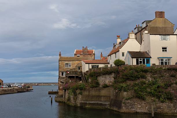 istock A quaint coastal village sits along a harbor under a cloudy sky. 2224680963