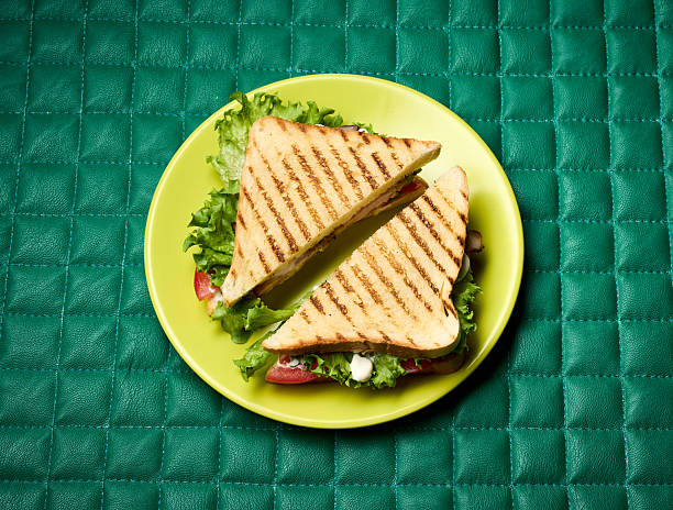 club sandwich on green plate on checkered leather background, top view