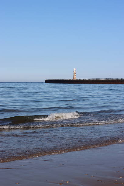 istock View from a beach to a lighthouse at the end of a pier 2224691118