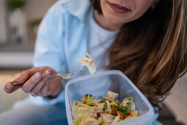 istock Woman eating healthy salad from plastic container at home 2224691211