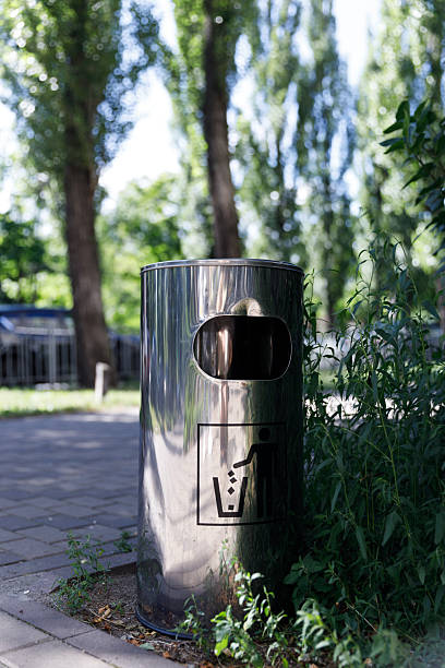 istock A Modern Stainless Steel Trash Bin Surrounded by Lush Greenery in a Park, Encouraging Proper Waste Disposal with an Illustrated Sign for Environmentally Conscious Visitors 2224693143