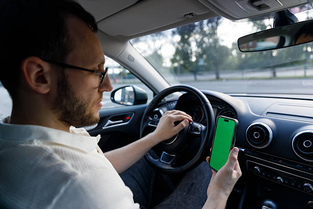 istock A Focused Individual Inside a Car Holds a Smartphone with a Green Screen While Preparing to Drive, Merging Technology with Modern Life 2224693442