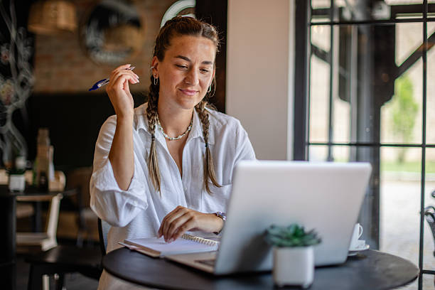 istock Young woman working on laptop at a cafe while taking notes and enjoying a productive morning 2224694996