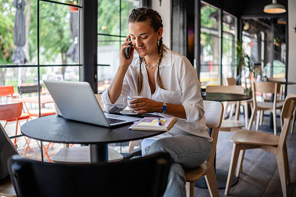 istock Woman engages in work at a modern cafe while talking on the phone and enjoying coffee 2224698059
