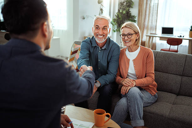 istock Mature couple shaking hands with agent over agreement at home 2224698093