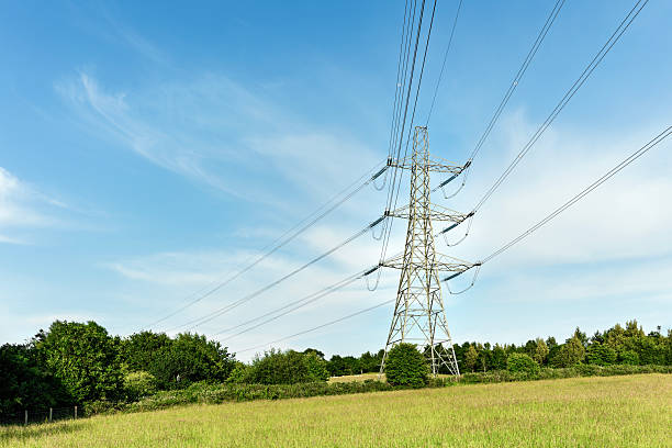 istock High Voltage Pylon and Power Lines in a Grassy Field Against a Blue Sky 2224700448