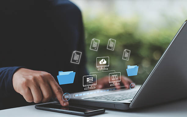 istock A business professional using a laptop and smartphone to transfer digital files through cloud computing technology. Secure data management, online document file sharing,  upload and download process. 2224700643