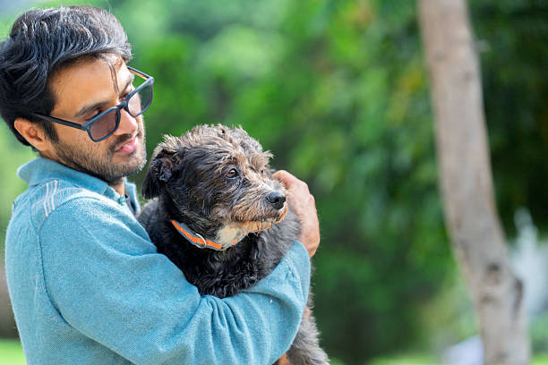 istock Young man hugging his mixed-breed dog in the park 2224704718