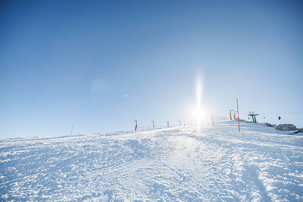 A breathtaking view of a snow-covered ski slope in the European Alps under a clear blue sky. The sunlight creates a serene atmosphere, perfect for winter sports enthusiasts. Ideal for skiing and enjoying the beauty of nature.