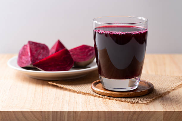 Fresh beetroot juice in glass on wooden background