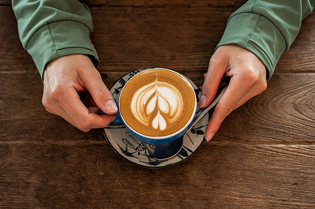 Woman hands holding a cup of hot Cappuccino coffee before drinking.