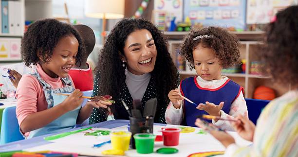 istock Education, kids and teacher painting hands for art, creative talent and motor skill development in preschool class. Learning, students drawing and happy children in lesson with watercolor with brush 2224712672