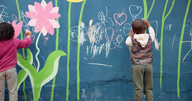 istock Wall, children and drawing with chalk for education, cognitive development and creativity in school. Back, students and kids with learning for writing mural, inspiration and outdoor in kindergarten 2224712710
