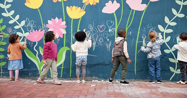 istock Wall, kids and drawing with chalk for education, cognitive development and creativity in school. Back, students and children with learning for writing mural, inspiration and outdoor in kindergarten 2224712711