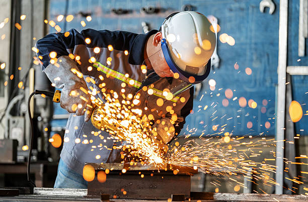 istock Experienced engineer wearing protective workwear, safety goggles, and face shield grinding a steel workpiece using industrial equipment. Sparks fly in all directions, highlighting skill, precision, and workplace safety in heavy industry and metal fabricat 2224716847