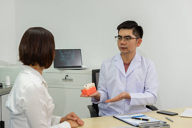 istock Dentist explains dental care to patient using model 2224721547