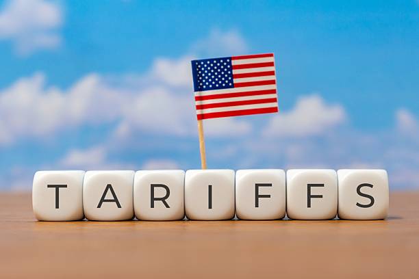 istock Cubes spelling TARIFFS are arranged in a line with a small American flag. 2224723345