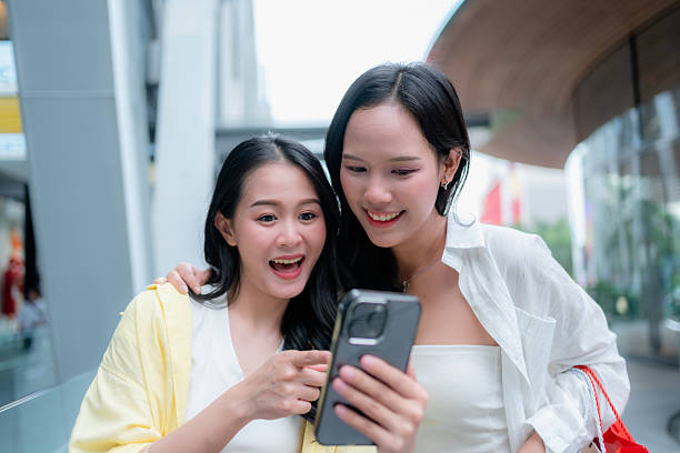 istock Excited Asian Women Looking at Smartphone While Shopping 2224726784