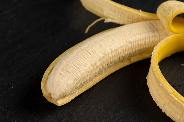 open ripe yellow banana on a black slate board, ripe and sweet yellow banana on a kitchen board made of black stone
