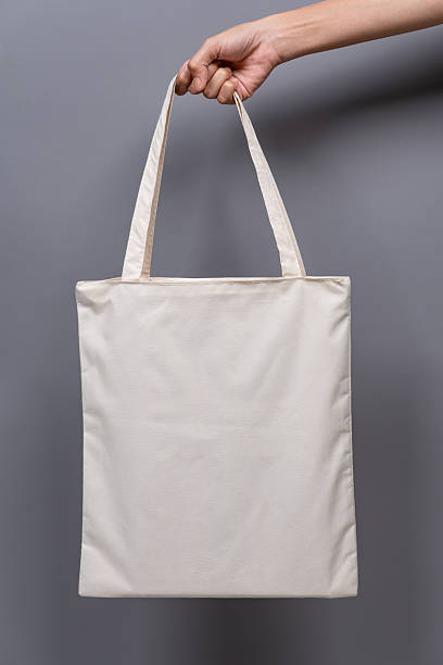 istock Woman’s Hand Holding Blank Canvas Tote Bag, Eco-Friendly Reusable Fabric with Handle, Close-Up Mockup, No Plastic and Environmental Concept 2224730289