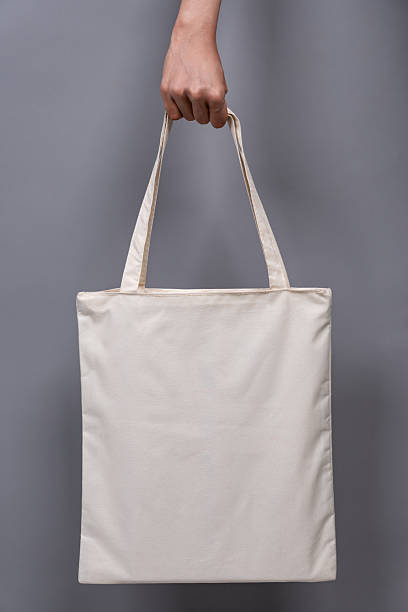 istock Woman’s Hand Holding Blank Canvas Tote Bag, Eco-Friendly Reusable Fabric with Handle, Close-Up Mockup, No Plastic and Environmental Concept 2224730312