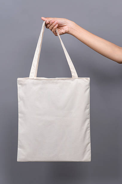 istock Woman’s Hand Holding Blank Canvas Tote Bag, Eco-Friendly Reusable Fabric with Handle, Close-Up Mockup, No Plastic and Environmental Concept 2224730318