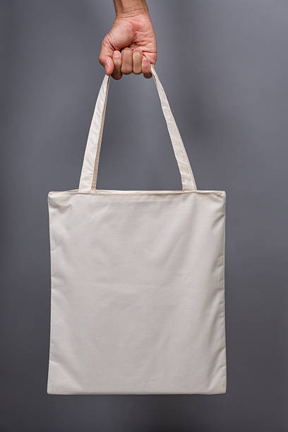 istock Woman’s Hand Holding Blank Canvas Tote Bag, Eco-Friendly Reusable Fabric with Handle, Close-Up Mockup, No Plastic and Environmental Concept 2224730383