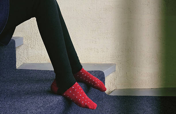A personal perspective of a woman's feet in funny pink toe socks on gray carpet.