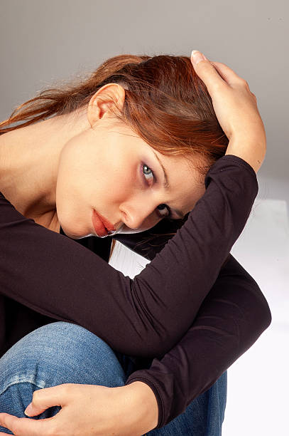 Portrait of a depressed young woman holding head in hands looking at the camera