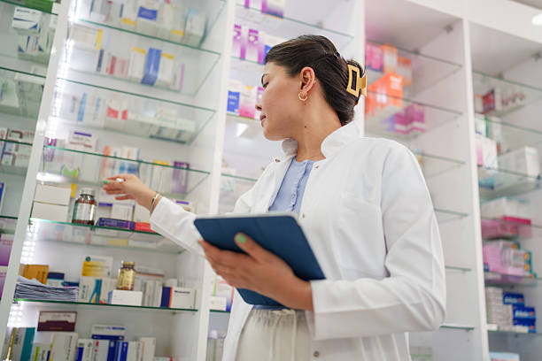 istock Young Female Pharmacist Organizing Shelves with Digital Tablet 2224737463