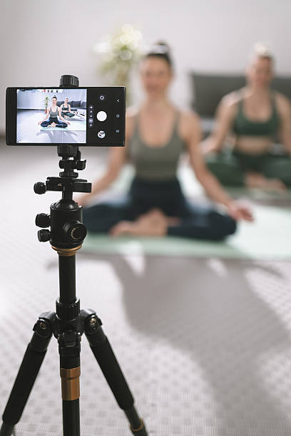 istock Group of individuals practicing yoga during a virtual session at home with a smartphone on a tripod recording their session 2224743911