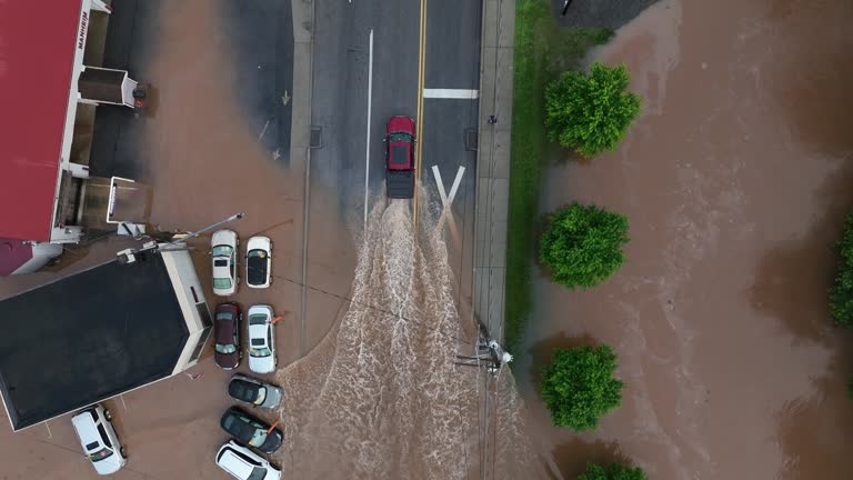 Red Pickup truck driving through dirty flooded streets after hurricane. Powerful vehicle arriving asphalt street in American town. Aerial top down tracking shot.
