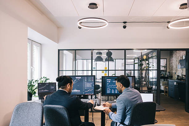 istock Two Businessmen Discuss Financial Data on Monitors in a Modern Office Setting 2224746827