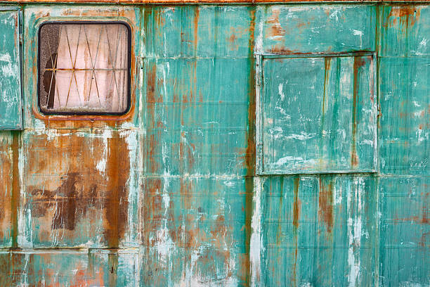 Photo of rusty abandoned metal van left in nature. Trees are seen on the backgraound. No people are seen in the frame. Shoot under daylight.